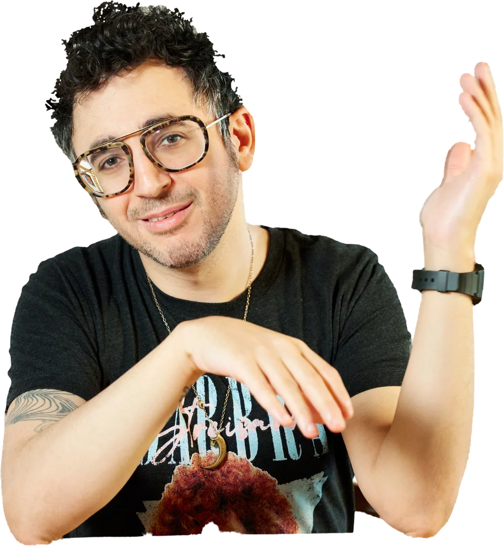 David Cooper, host of The Last Show, raising one hand and smiling at the camera